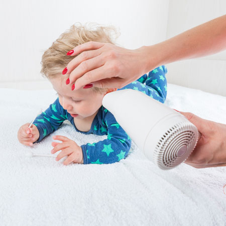 Lady using a hair dryer on a baby