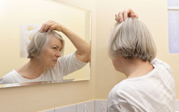 Woman checking hair loss in the mirror